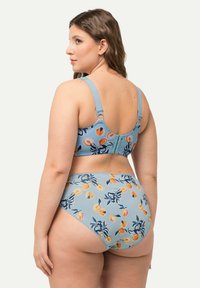 Conjunto de bikini azul con un patrón floral en tonos naranjas y verdes. La parte de arriba tiene tirantes ajustables y un cierre en la parte de atrás; la parte inferior es de tiro alto.