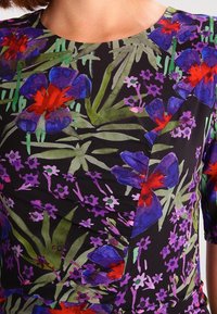 Vestido floral con fondo negro, flores moradas y rojas, hojas verdes y un diseño fruncido. Mangas cortas y escote redondo.