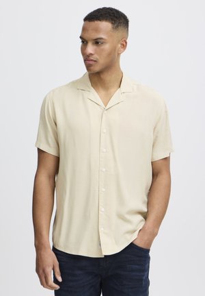 Kortærmet beige skjorte med afslappet krave, der har en knaplukning foran og et glat, let materiale.
