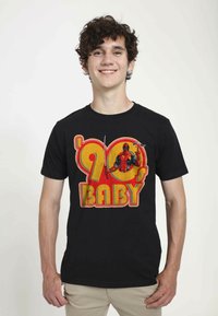 Černé bavlněné tričko s barevným grafickým motivem inspirovaným 90. lety, s textem „'90s BABY“ a ilustrací postavy, která drží meč.