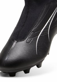 Scarpa da calcio nera con una tomaia sintetica testurizzata, colletto simile a un calzino e accenti bianchi; presenta punte moldate per la trazione.
