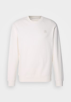 Bílá mikina vyrobená z měkké látky, s kulatým výstřihem, dlouhými rukávy, žebrovanými manžetami a malým čtvercovým logem na hrudi.