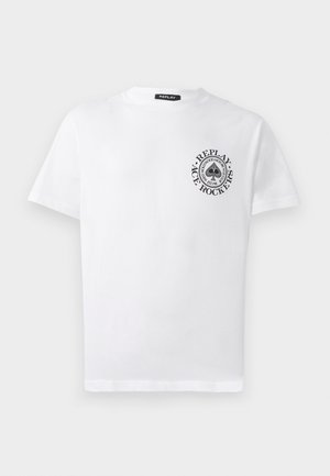 Bílý bavlněný tričko s kruhovým černým logem na levé části hrudi s textem, krátkými rukávy a běžným kulatým výstřihem.