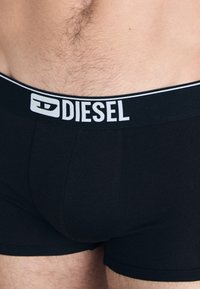Black boxer briefs made of cotton with a snug fit. The elastic waistband features the "DIESEL" logo in white on the front.