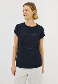 T-shirt en coton bleu marine à manches courtes, arborant un imprimé textuel graphique « FAIS CONFIANCE À TON IMAGINATION » dans un design contrastant.