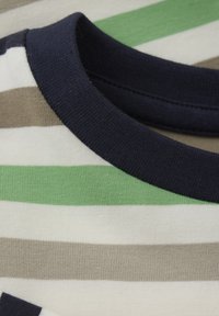 Pasiasta koszulka z pionowymi zielonymi, beżowymi i białymi paskami oraz granatowym ściągaczem. Wykonana z miękkiej bawełny o gładkiej fakturze.