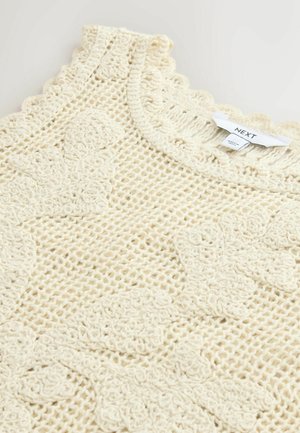 Cremefarvet hækletrøje med blomsterprint og bølget udskæring, der viser et hvidt Next-mærke.