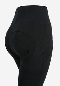 Leggings neri a vita alta con pannelli testurizzati, design senza cuciture e una piccola accentatura del logo sul lato. Materiale elastico e aderente.