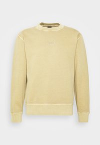 Ljusgul sweatshirt tillverkad av mjukt tyg, med rund halsringning, ribbade ärmslutar och en diskret logotyp på bröstet.