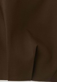 Gros plan sur un tissu marron foncé avec une texture de tissage diagonal visible et un détail de bord plié.