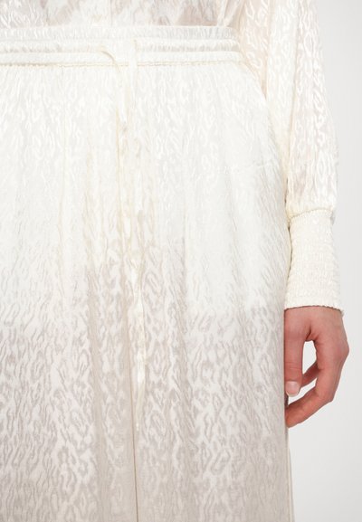 Cream-colored dress featuring a textured, patterned fabric with an elastic waistband and gathered sleeves, providing a lightweight, airy appearance.
