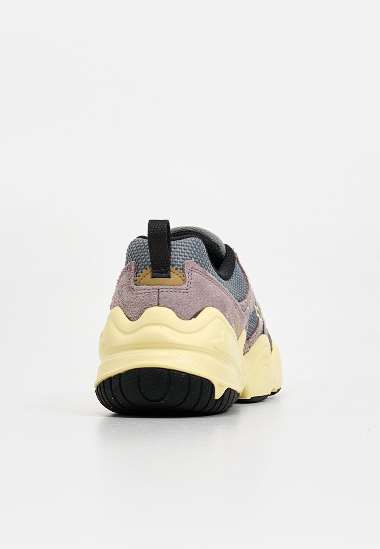 Sneaker z teksturowaną szaro-sieciową cholewką, fioletowymi zamszowymi akcentami, żółtą masywną podeszwą środkową i czarną gumową podeszwą zewnętrzną. Posiada uchwyt do zakupu.