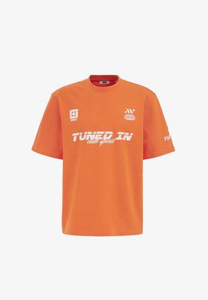 Oranges T-Shirt mit kurzen Ärmeln mit weißem Text "TUNED IN club spirit" und kleinen grafischen Logos auf Brust und Ärmel.