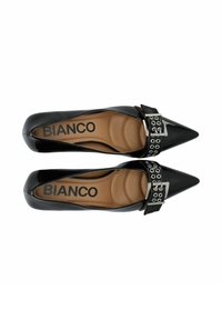 Zapatos negros de punta afilada con un acabado brillante de charol, una correa ancha y detalle de hebilla plateada, y una plantilla de color marrón claro acolchada.