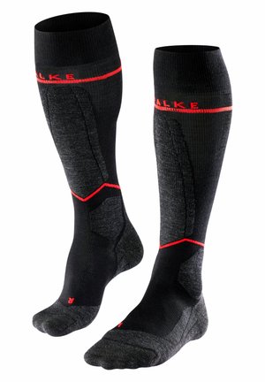 Chaussettes noires jusqu'aux genoux avec un design texturé, comportant des accents rouges et des zones renforcées pour plus de durabilité. Fabriquées en matériau synthétique.