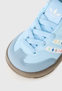 Baskets bleu clair avec une surface texturée, des côtés rembourrés, des lacets assortis et des accents zigzag multicolores sur le côté.