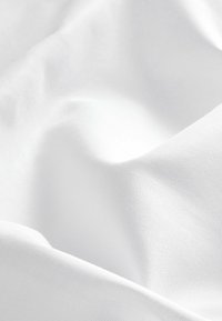 Tissu blanc avec une texture lisse, montrant de douces plis et creux, et un subtil éclat. Le matériau semble léger et doux.