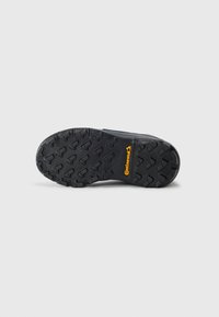 Schwarze Gummisohle mit tiefem Profil und Continental-Branding in Gelb. Texturierte Oberfläche für Grip und Stabilität.