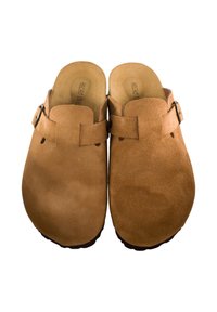 Zuecos de ante marrón con la punta cerrada, dos correas y una hebilla de metal. La plantilla es color beige y la suela presenta patrones texturizados.