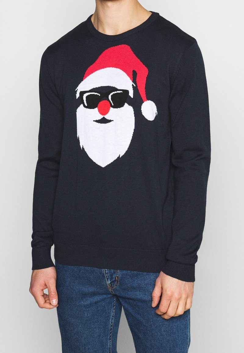 Mörkblå stickad tröja med en grafik av Santas ansikte, som har en röd mössa, vit skägg, svarta solglasögon och en röd näsa. Ribbad mudd och nederkant.