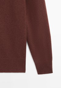 Brązowy sweter z dzianiny o miękkiej teksturze, z prążkowanym wykończeniem u dołu oraz na mankietach, ze skosem w okolicy łokcia dla swobodnego kroju.