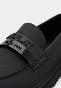 Ballerines noires en cuir lisse. Elles présentent une sangle brillante avec le logo "Replay" et un détail en relief "since 1981".