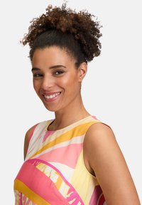 Robe sans manches colorée avec des rayures roses, jaunes et blanches en motif radial, fabriquée en tissu doux avec une texture lisse.