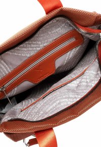 Oranža austas auduma soma iekšpuse ar pelēku oderi, uz kuras ir balti burti, rāvējslēdzēja kabata un ādas elementi; ietver rāvējslēdzēja aizdari.