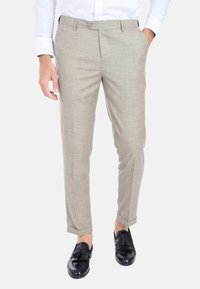 Pantaloni in lino beige con un delicato motivo a quadri, slim fit, dotati di tasche laterali e chiusura con bottone. Abbinati a mocassini neri.