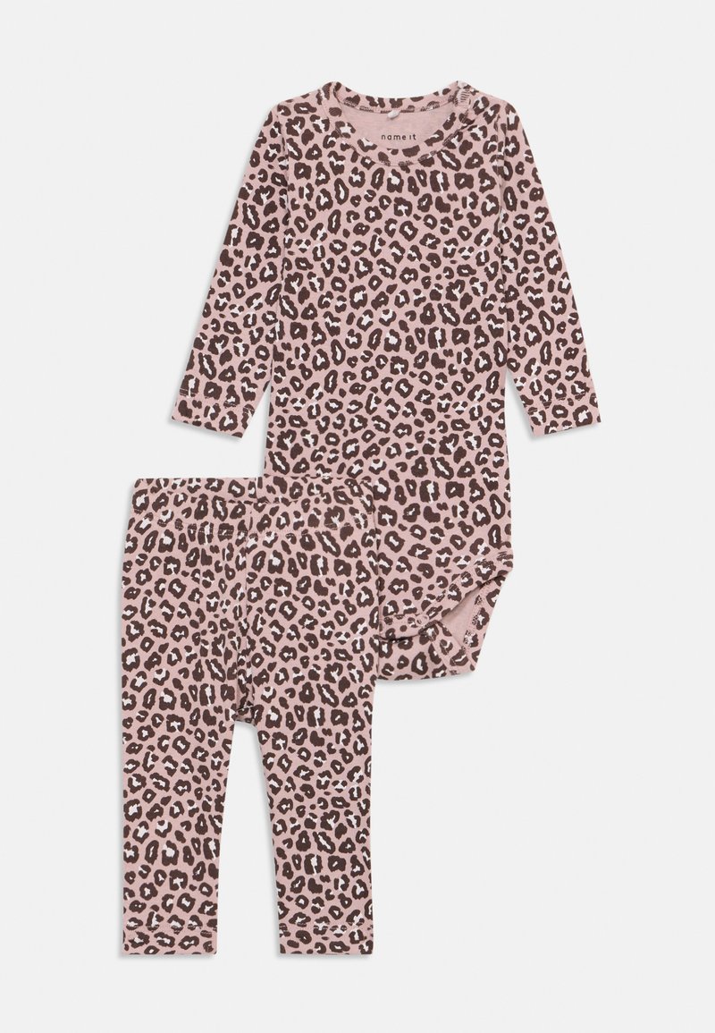 Ilgų rankovių rožinės spalvos leopardų rašto bodis su atitinkamomis antblauzdėmis. Minkšta medvilnės medžiaga, apvalus kaklo iškirpimas ir tamprus juosmuo.