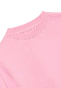 Różowa koszulka typu crew neck wykonana z miękkiej bawełny, z widocznym przeszyciem wzdłuż kołnierza i szwu na ramieniu.