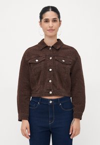 Bruine, cropped spijkerjas met een luipaardprint, knoopsluiting, twee borstzakken en zilverkleurige accenten. Draagt met donkerblauwe jeans.