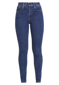 Jeans ajustados de mezclilla azul oscuro, diseño de cintura alta con el clásico estilo de cinco bolsillos, trabillas y detalles de costura en contraste.