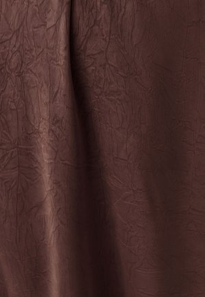 Ciemnobrązowa tkanina o pomarszczonej fakturze i subtelnych fałdach tworzących zróżnicowanie światła i cienia na powierzchni.