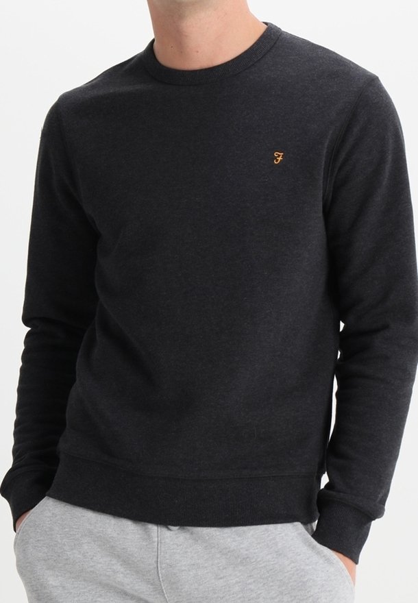 Sudadera gris oscuro de una tela suave y texturizada, con cuello redondo y puños acanalados. Presenta un pequeño logo naranja en el pecho.