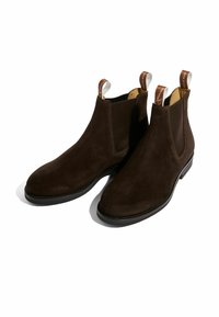 Botas Chelsea de ante marrón con paneles laterales elásticos y tiradores, que cuentan con una puntera redondeada y una suela plana de goma para mayor estabilidad.
