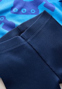 Blue t-shirt with dark blue roller skate print, paired with dark navy ribbed leggings, featuring a smooth texture and elastic waistband.