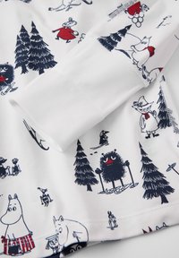 White long-sleeve shirt featuring a playful print with various cartoon characters and trees in navy, red, and black against a white background.