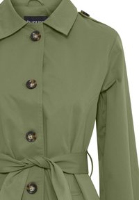 Trench coat verde oliva con colletto, quattro bottoni e cintura in vita. Presenta una texture liscia e una vestibilità su misura. I bottoni hanno un design tartaruga.