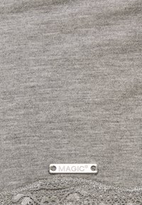 Camisola de tecido cinza com pequenas costelas e um acabamento de renda na barra. Uma etiqueta prateada diz "MAGIC®" perto da parte inferior.