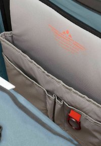 Sac en tissu gris avec une poche, doté d'une sangle d'accent rouge. Texture lisse, qualité imperméable et détails imprimés en orange.