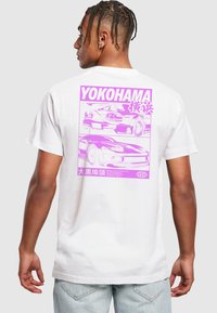 Hvid bomulds t-shirt med et stort pink grafisk motiv af to biler og japansk tekst på ryggen. Designet har kraftige konturer og minimal detaljering.