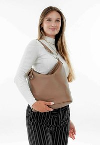 Sac à main en cuir tan au design décontracté, ouverture zippée et finition texturée. Présente une large bandoulière et des accessoires en métal.