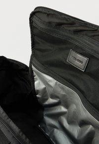 Εσωτερικό μαύρης τσάντας με δίχτυα και αντανακλαστική ασημένια επένδυση. Περιλαμβάνει ετικέτα με την επιγραφή "TIER-ONE". Κλείσιμο με φερμουάρ στο πάνω μέρος.