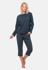 Mørkeblå langærmet top kombineret med stribede cropped bukser, begge lavet af blødt stof. Toppen har en afslappet pasform, og bukserne har en snor i taljen.