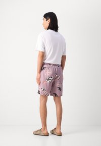 Shorts de bain violets avec un motif de parasols de plage et de mains. Les shorts ont une taille élastique et sont fabriqués en tissu léger.