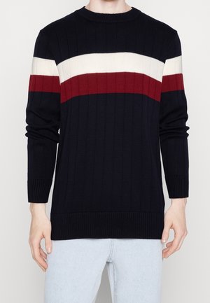 Pull en maille marine avec des rayures horizontales blanches et rouges. Poignets et ourlet côtelés, col rond et tissu texturé.