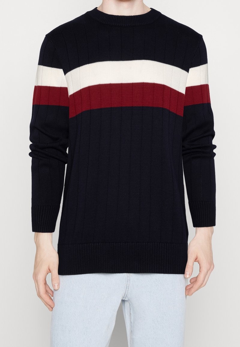 Maglione in maglia blu navy con strisce orizzontali bianche e rosse. Polsini e orlo a coste, con scollatura tonda e tessuto testurizzato.