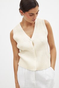 Cremfarbener, gerippter Tanktop mit V-Ausschnitt, der vorne drei Knöpfe hat und eng sitzt. Der Stoff hat eine weiche Textur und vertikale Linien.