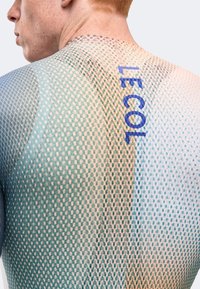 Junge Person trägt ein mehrfarbiges, netzartiges Hemd mit dem vertikal in Blau auf dem oberen Rücken gedruckten Schriftzug „LECOL“.